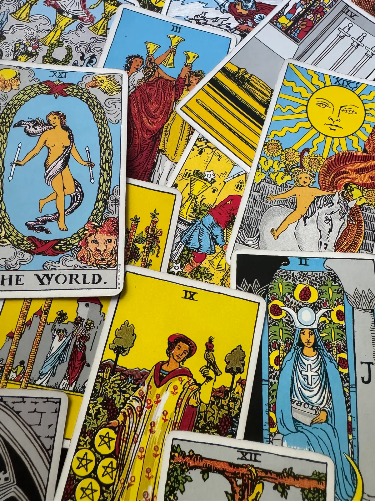 Overlapping tarot cards featuring The World, Three of Cups, The Sun, and The High Priestess.